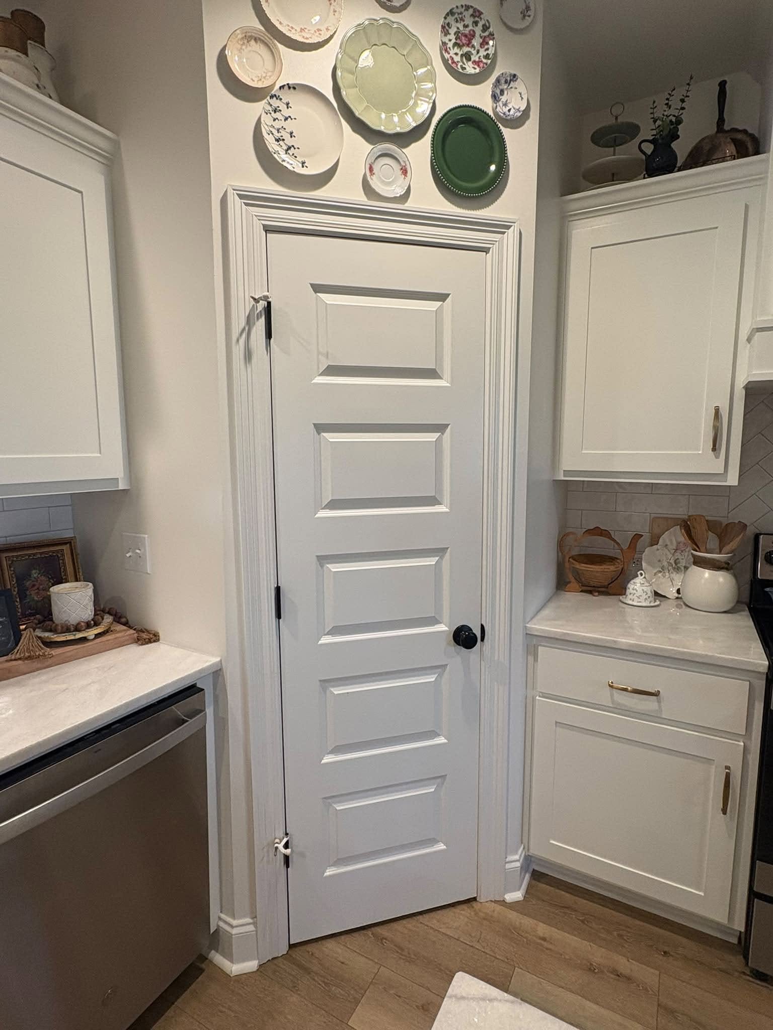 White pantry door surrounded by the finished kitchen cabinetry